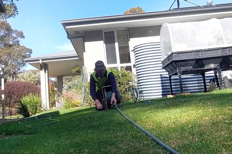 The merimbula downpipe cleaner is concluding his day by securing his hose.